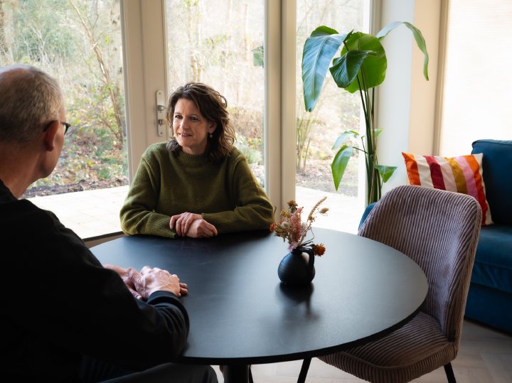 Ouder en coach voeren een gesprek aan tafel