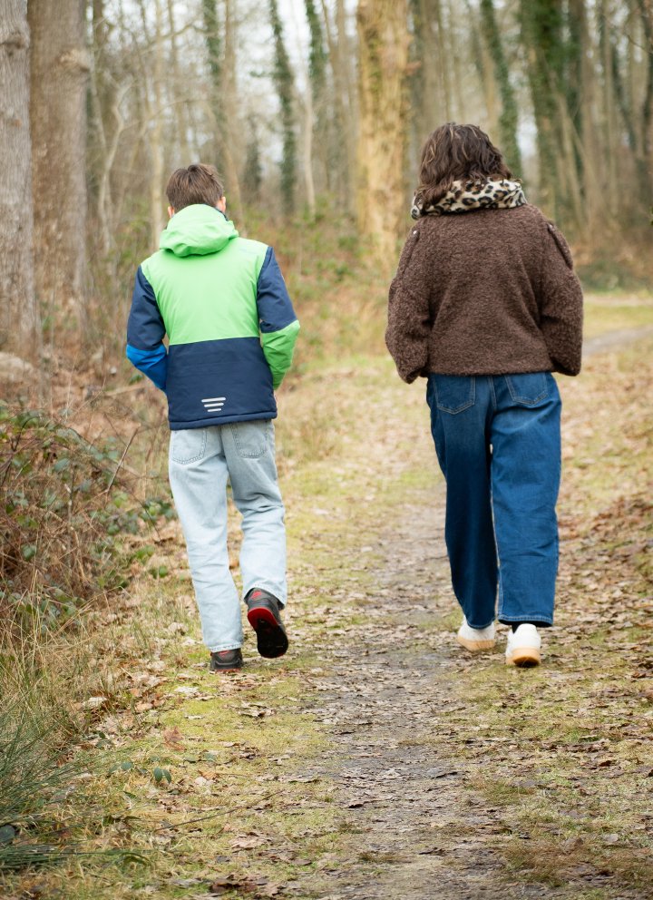 Coach en jongere wandelen samen over een bospad