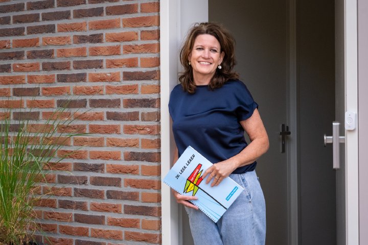 Vrouw houdt het werkboek Ik Leer Leren vast bij de ingang
